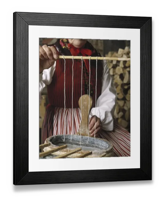 Framed Print : Making candles. A woman dressed in traditional Swedish folk costume are making candles