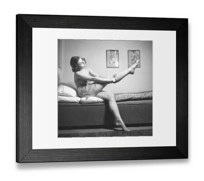 Framed Print : Nylon stockings in the 1940s. A young woman is getting dressed in the moring