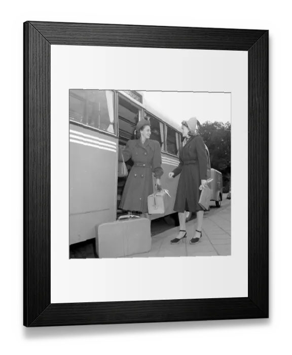 Framed Print : Women's fashion in the 1940s. A young woman in a typical 1940s coat, with matching hat, shoes, gloves and handbag. She steps off the bus carrying her luggage and is greeted by a lady friend also in a typical 1940s coat Framed Print : Women's fashion in the 1940s. A young woman in a typical 1940s coat, with matching hat, shoes, gloves and handbag. She steps off the bus carrying her luggage and is greeted by a lady friend also in a typical 1940s coat