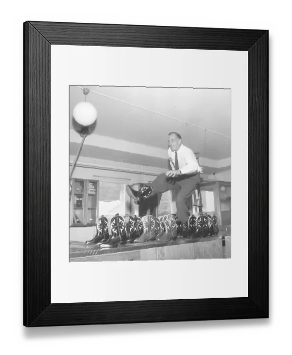 Framed Print : Cowboy boots. A man is playing around and dancing on a table with cowboy boots. Another dozen of cowboy boots are standing on the side. Sweden 1956. Photo Kristoffersson Ref BX20-6