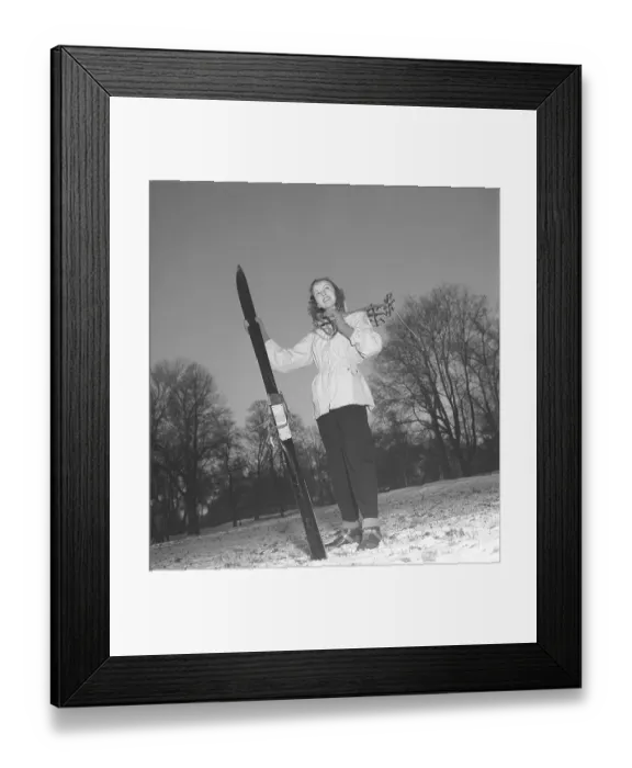 Framed Print : Winter in the 1940s. A young woman is wearing the typical 1940s winter sports clothes. Dressed in a practical wind jacket, ski pants and with a pair of skis and poles. Sweden 1948. Photo Kristoffersson ref Y10-4