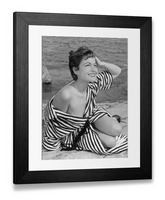 Framed Print : 1950s summer. A young woman wearing a stripe patterned bathrobe on the beach a sunny summer's day Framed Print : 1950s summer. A young woman wearing a stripe patterned bathrobe on the beach a sunny summer's day