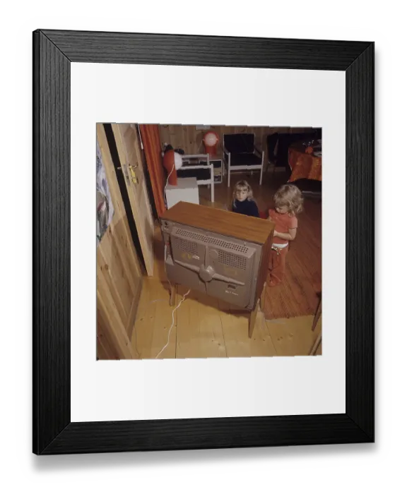 Framed Print : Television in the 1960s. Two girls are sitting in front of a television set with her eyes on the screen and the program