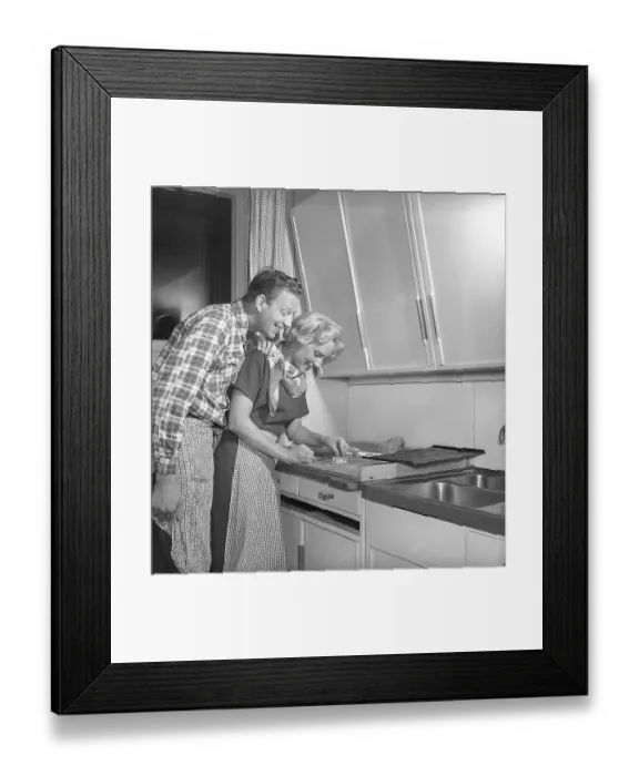Framed Print : In the kitchen in the 1950s. Ayoung couple baking heart shaped gingerbread cookies for christmas