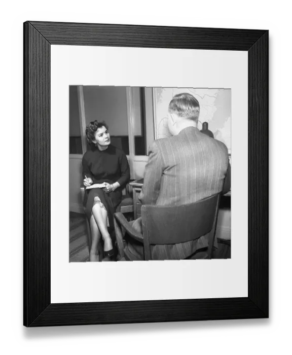 Framed Print : Office girl in the 1950s. A woman is sitting with a notebook in her lap writing notes of what the man says, possibly a letter that she later will type. To have a secretary was more common in the past then today Framed Print : Office girl in the 1950s. A woman is sitting with a notebook in her lap writing notes of what the man says, possibly a letter that she later will type. To have a secretary was more common in the past then today