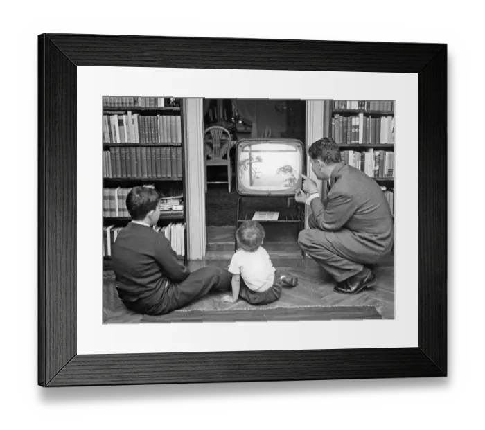 Framed Print : Television in the 1950s. A father with his children in front of the television set looking at a children's program