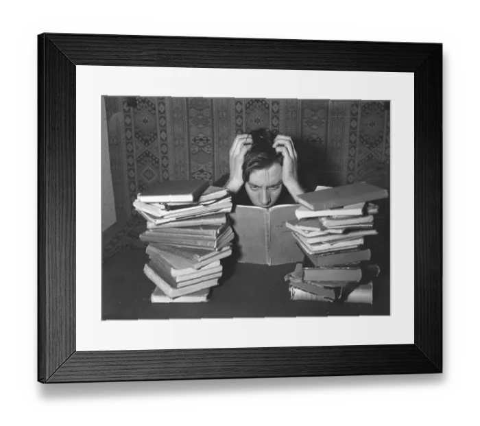 Framed Print : Reading in the 1940s. A young man with his study books in front of him looks as if he is studying hard