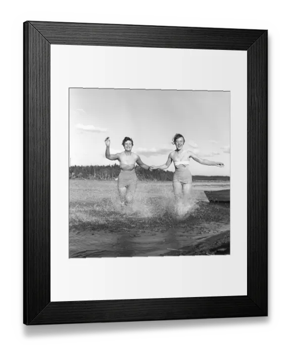 Framed Print : 1950s summer. Two young women runs on the shallow part of the beach and the water splashes Framed Print : 1950s summer. Two young women runs on the shallow part of the beach and the water splashes