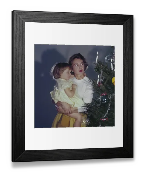 Framed Print : Christmas in the 1950s. A mother and her daughter is standing by the christmas tree Framed Print : Christmas in the 1950s. A mother and her daughter is standing by the christmas tree