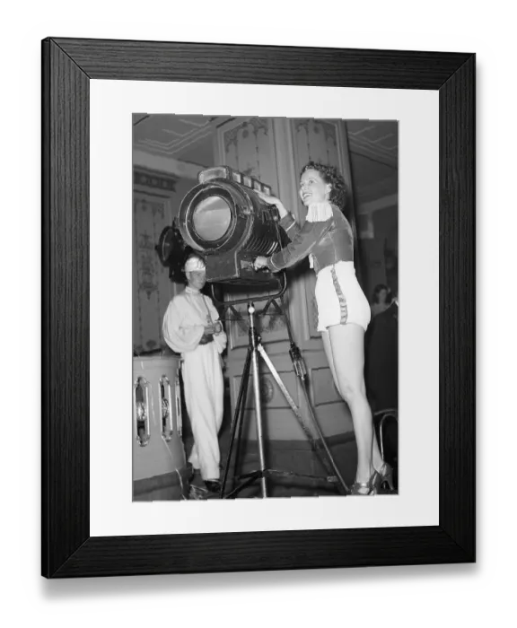 Framed Print : Film studio in the 1940s. A young woman pictured in a film studio beside a spotlight Framed Print : Film studio in the 1940s. A young woman pictured in a film studio beside a spotlight
