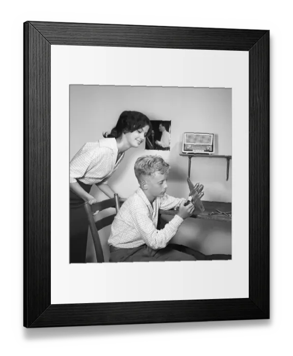 Framed Print : Hobby in the 1950s. A boy is sitting at a table with a plastic model of an American bomb aircraft B-26 Framed Print : Hobby in the 1950s. A boy is sitting at a table with a plastic model of an American bomb aircraft B-26