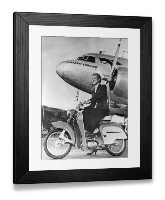 Framed Print : Woman of the 1950s. A young woman with a new Monark moped in front of a passenger plane