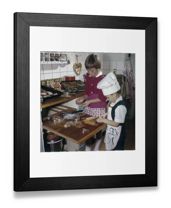 Framed Print : Christmas in the 1950s. A girl and a boy is busy in the kitchen baking ginger bread
