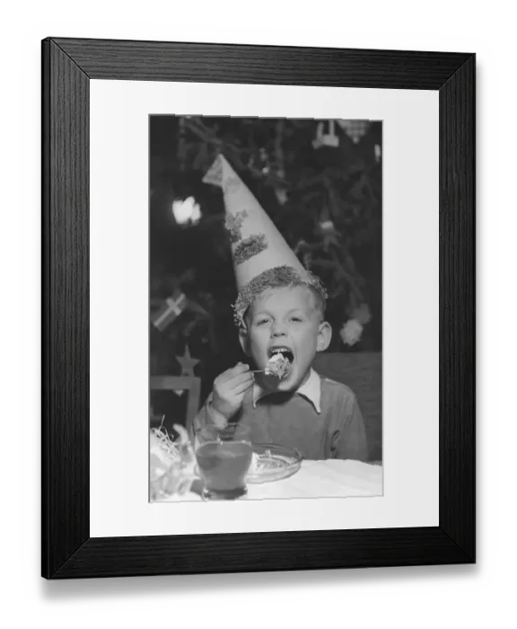 Framed Print : Christmas in the 1950s. A boy on a christmas party is eating cake and drinking lemonade Framed Print : Christmas in the 1950s. A boy on a christmas party is eating cake and drinking lemonade