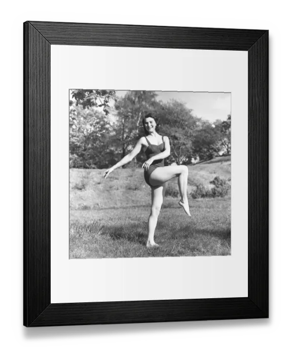 Framed Print : Woman in the 1950s. A dark haired women is doing gymnastics outdoors on a summers day Framed Print : Woman in the 1950s. A dark haired women is doing gymnastics outdoors on a summers day