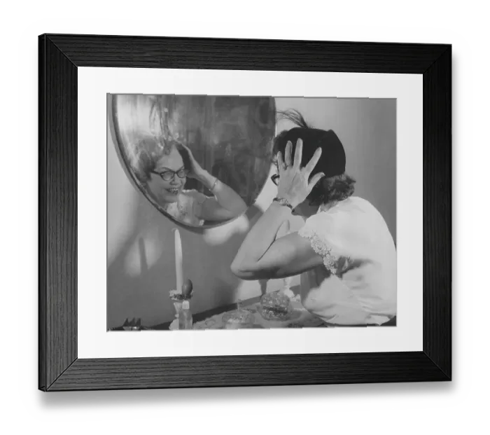 Framed Print : In the 1950s. A lady looks her self in the wall mirror to see that her hat looks good on her Framed Print : In the 1950s. A lady looks her self in the wall mirror to see that her hat looks good on her