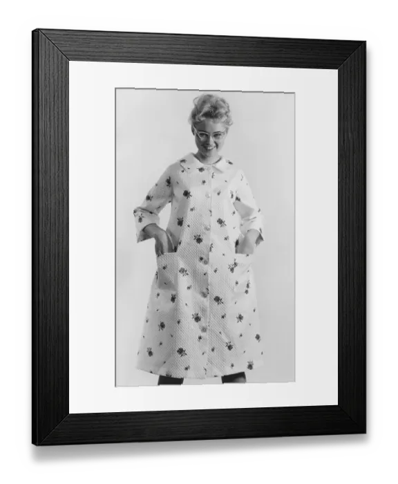 Framed Print : 1950s glasses and fashion. A young smiling woman is dressed in a morning gown Framed Print : 1950s glasses and fashion. A young smiling woman is dressed in a morning gown