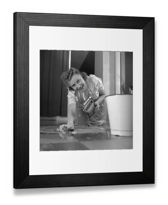 Framed Print : Cleaning the floor back then. A young woman is lying on the floor and is scrubbing to get the floor clean