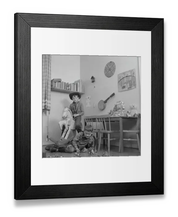 Framed Print : Boys in the 1950s. Two boys in their play room are dressed as cowboys. One is riding a wooden horse and one is playing with figures of cowboys and indians on the floor. Sweden 1953 Conard ref 2273