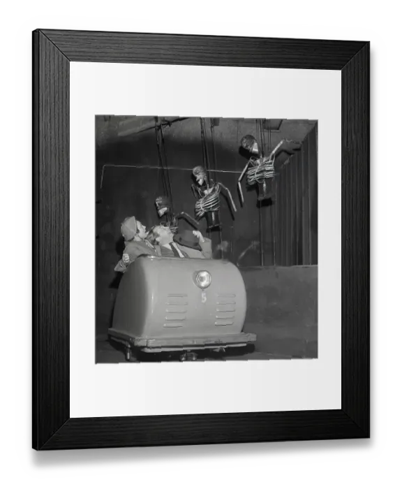 Framed Print : Amusement park in the 1950s. A couple passes skeletons in an amusement park ride Framed Print : Amusement park in the 1950s. A couple passes skeletons in an amusement park ride