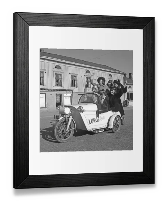 Framed Print : Driving in the 1940s. A man drives a three wheeled motorcycle and a group of women have joined the ride