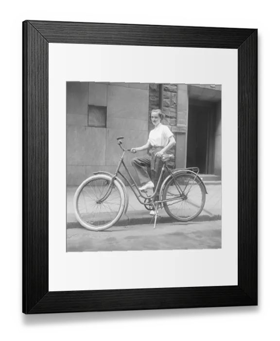 Framed Print : 1950s woman on a bicycle. A smiling young woman on a womens bicycle