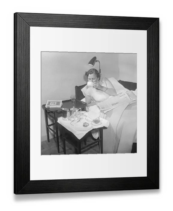 Framed Print : Woman of the 1950s. A young woman is lying in bed and serviced with a breakfast meal
