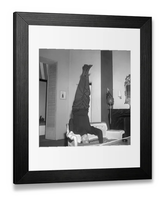 Framed Print : Man of the 1950s. A man standing on his head in a sofa