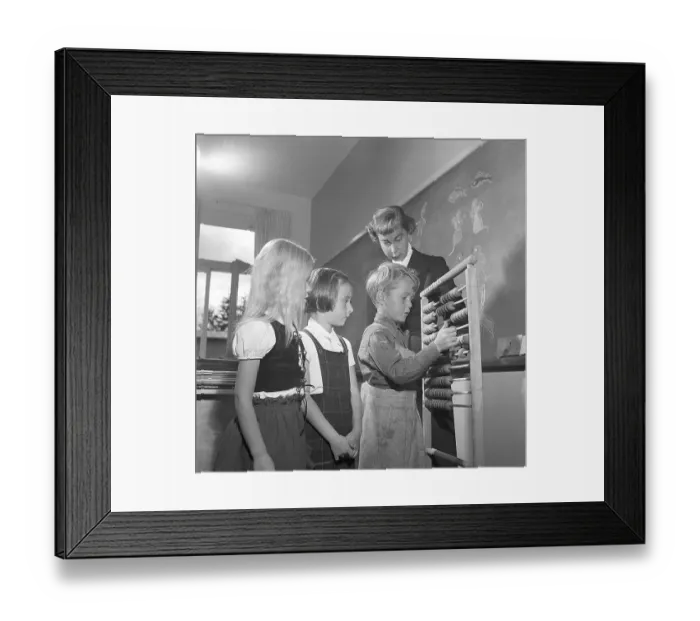 Framed Print : School in the 1950s. The female schoolteacher watches as her first grade pupils are learning how to count