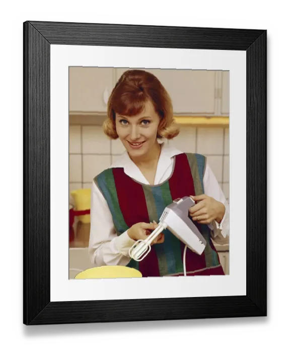 Framed Print : In the 1960s. A young woman pictured in the kitchen using an electric hand mixer