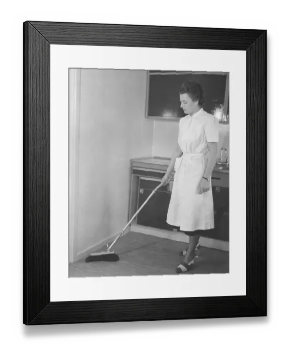 Framed Print : Cleaning day in the 1950s. A young woman dressed in a practical cleaning outfit