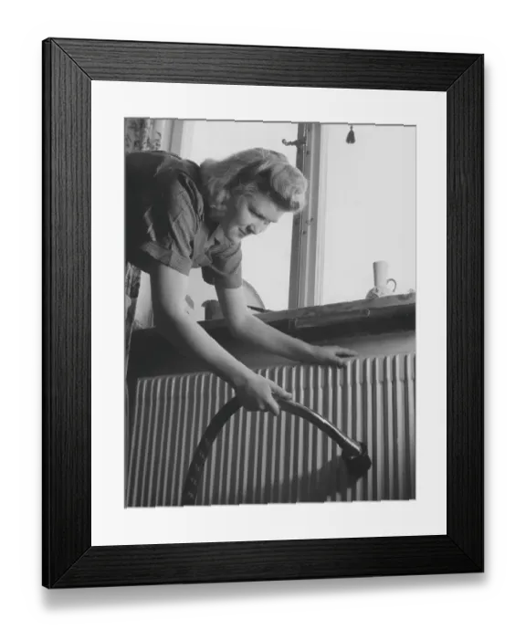 Framed Print : Cleaning day in the 1940s. A young woman is cleaning her apartment and is vacuuming the radiator below the window Framed Print : Cleaning day in the 1940s. A young woman is cleaning her apartment and is vacuuming the radiator below the window