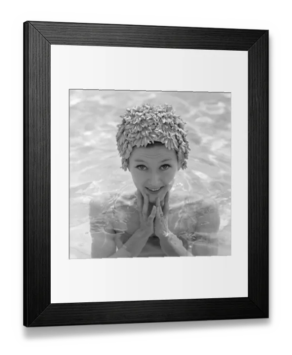 Framed Print : In the 1960s. A young woman pictured in the swimming pool wearing a typical 1960s bathing cap in a plastic material Framed Print : In the 1960s. A young woman pictured in the swimming pool wearing a typical 1960s bathing cap in a plastic material