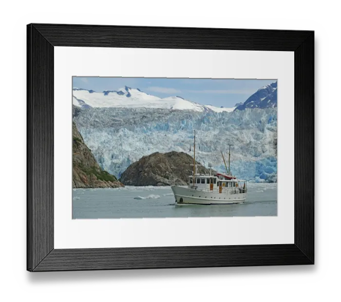Framed Print : Small boat in front of the ice front of a glacier calving into the sea Framed Print : Small boat in front of the ice front of a glacier calving into the sea