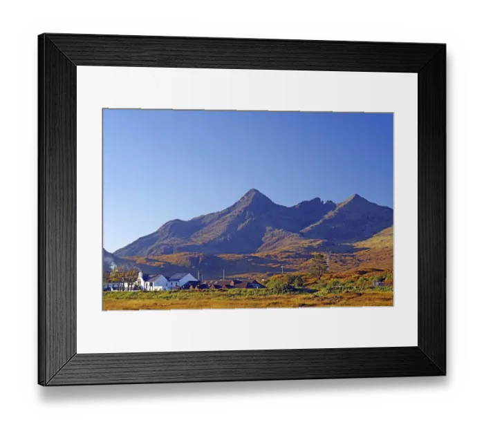 Framed Print : A small village lies against an impressive mountain backdrop under a clear blue sky