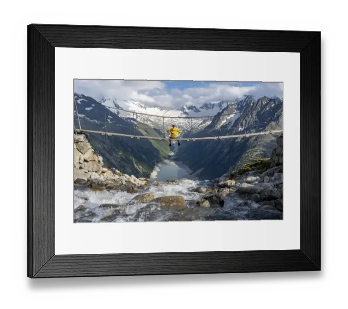 Framed Print : Mountaineer sitting on a suspension bridge over a mountain stream Alelebach