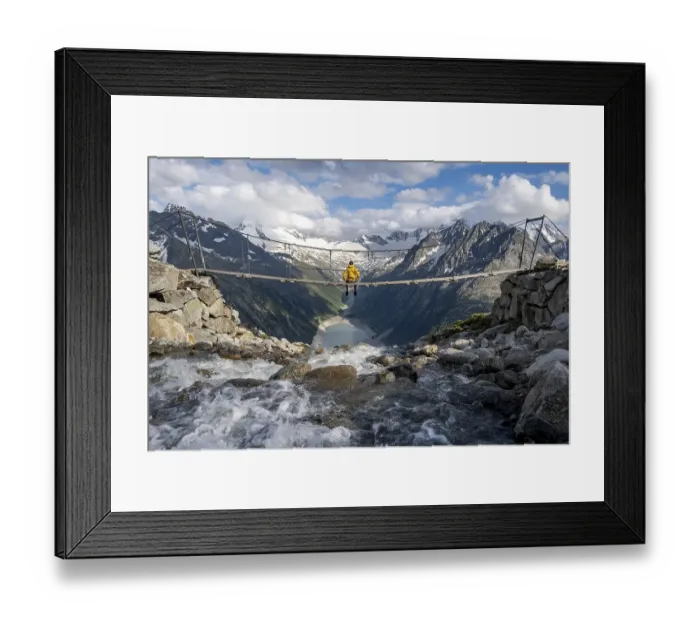 Framed Print : Mountaineer sitting on a suspension bridge over a mountain stream Alelebach