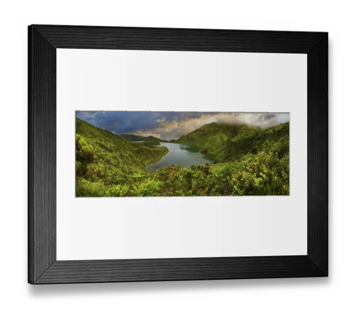 Framed Print : Panoramic view of a lake surrounded by green forested mountains under a dramatic sky Framed Print : Panoramic view of a lake surrounded by green forested mountains under a dramatic sky