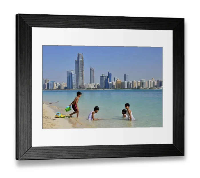Framed Print : Children playing in water, Abu Dhabi skyline in the back