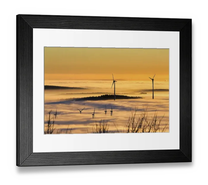 Framed Print : Wind turbines and forest rising from cloud cover
