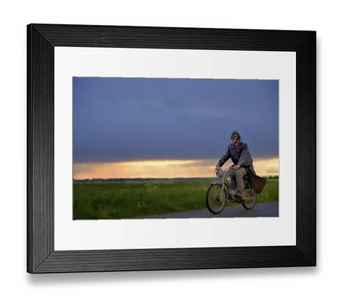 Framed Print : Vintage motorcyclist in front of a dramatic cloudy sky