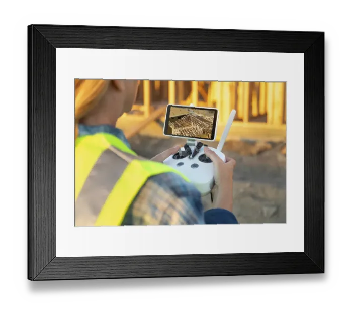 Framed Print : Female unmanned aircraft system (UAV) quadcopter drone pilot with controller inspecting new house framing