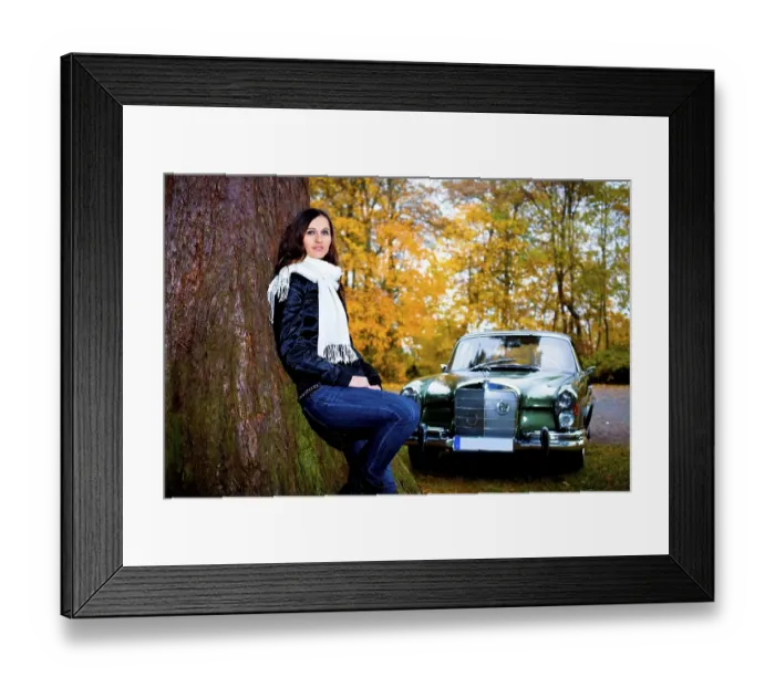 Framed Print : Young woman leaning against a tree in front of a vintage car