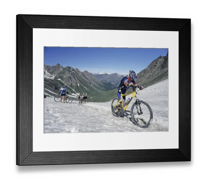 Framed Print : Mountain bike racers crossing a snow-covered mountain pass trail Framed Print : Mountain bike racers crossing a snow-covered mountain pass trail