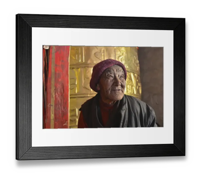 Framed Print : Nun, 76 years, in front of a huge golden prayer wheel Framed Print : Nun, 76 years, in front of a huge golden prayer wheel