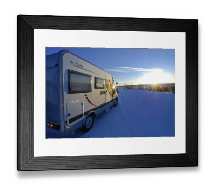 Framed Print : Camper driving through wintry landscape at sunset