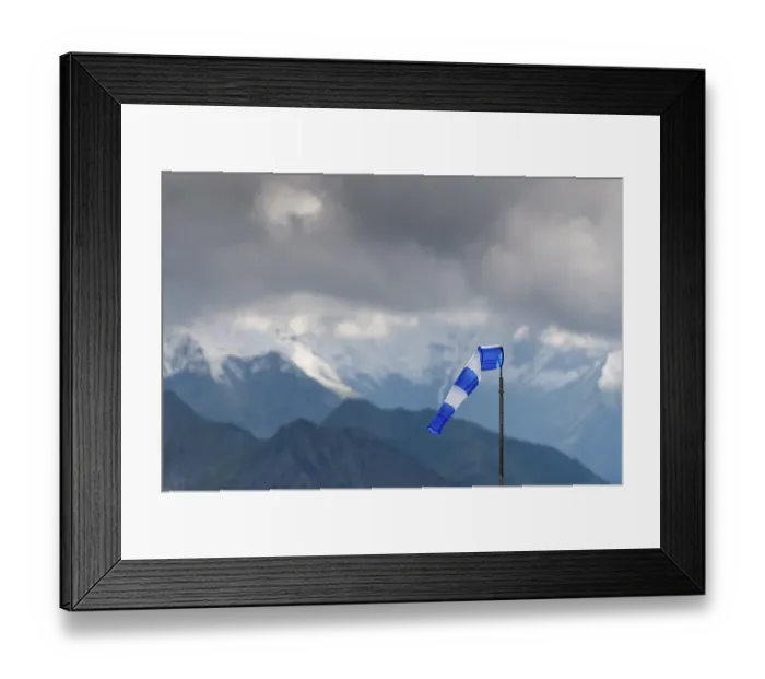Framed Print : Blue and white windsock on the summit of the Nebelhorn in front of the mountain range with dark clouds