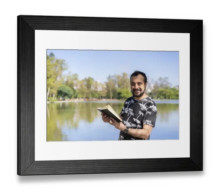 Framed Print : Mature man reading by a lake, enjoying free time on a sunny day