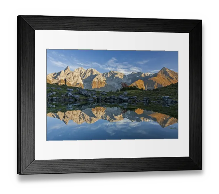 Framed Print : Hiker reflected in mountain lake in front of mountains