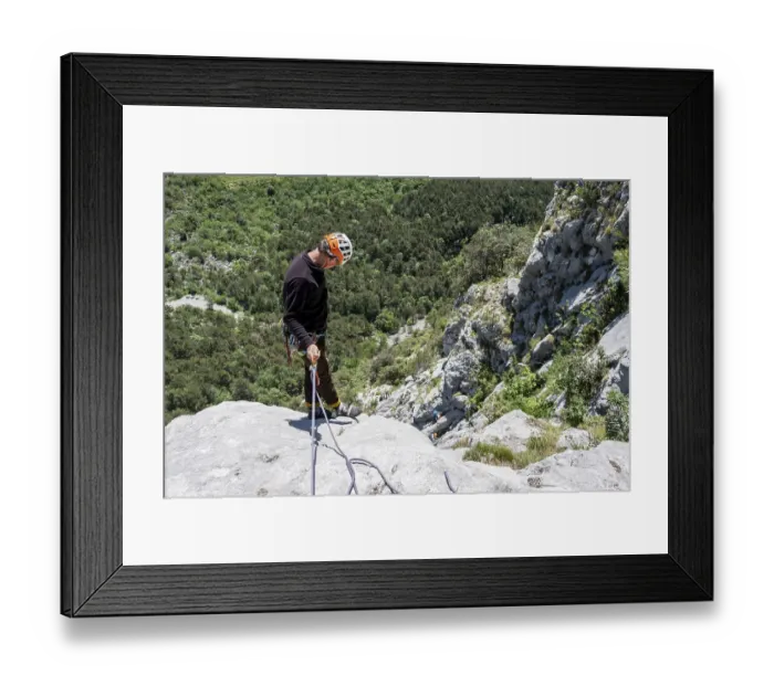 Framed Print : A climber in safety equipment descends a rocky mountain face